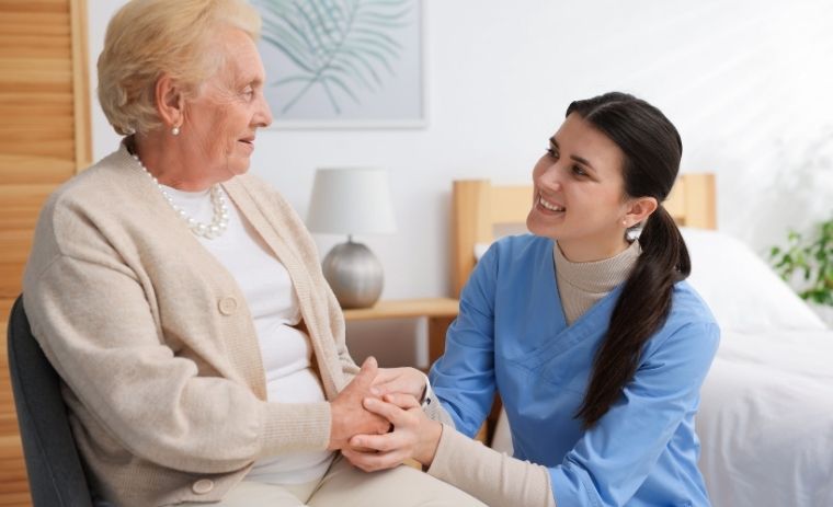 A compassionate caregiver holding hands with an elderly woman at home, illustrating how to choose the right home care service in Pennsylvania with PA Home Care Aid.