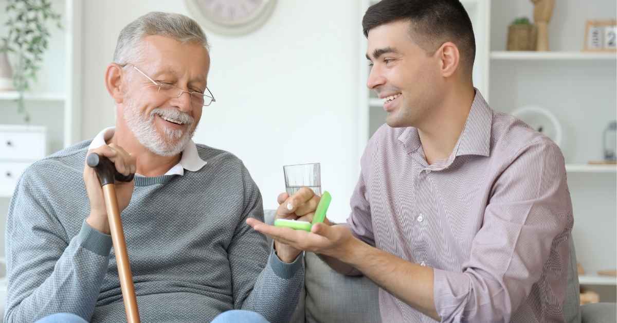 Home caregiver helping an elderly man with medication at home, showing a warning sign that a loved one needs home care for daily support and safety.