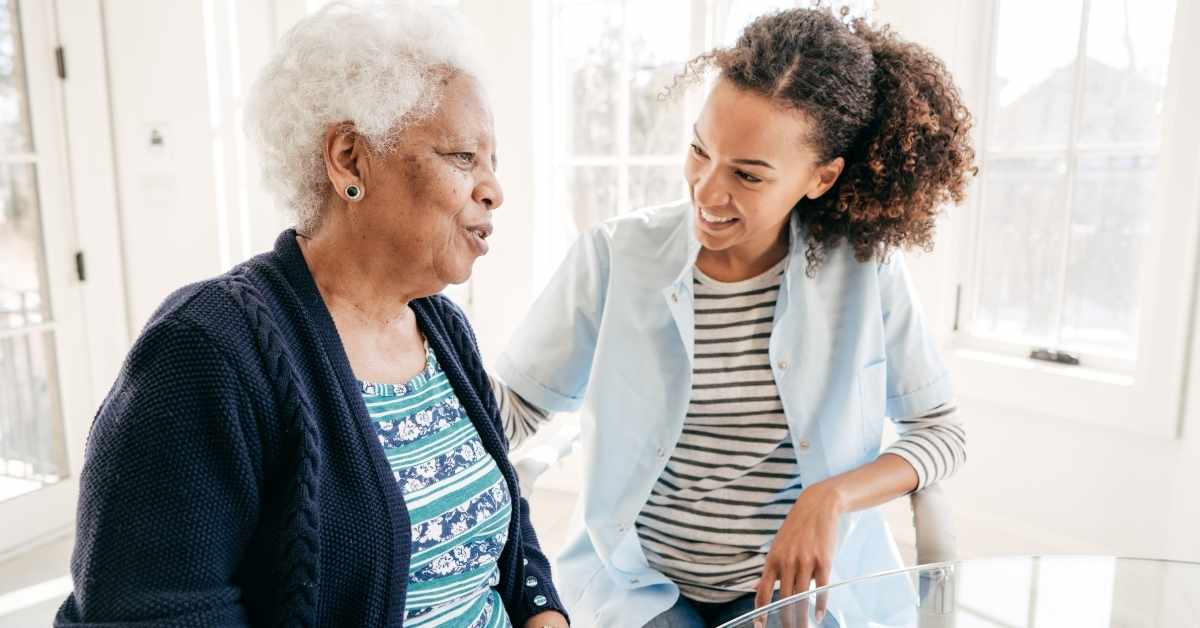 Caregiver offering in-home support and friendly conversation to an elderly woman, illustrating 9 common myths about home care.