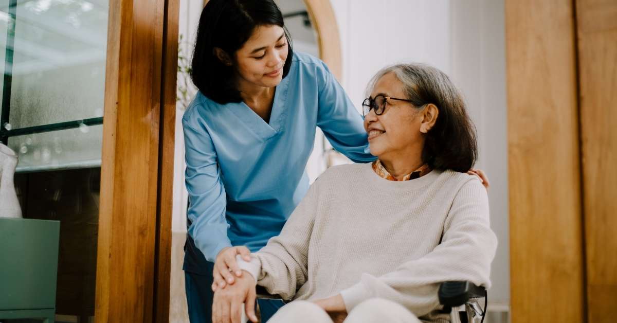 PA home care client smiling at caregiver while seated in wheelchair, illustrating the rights & responsibilities of home care clients in Pennsylvania with respectful in-home assistance.